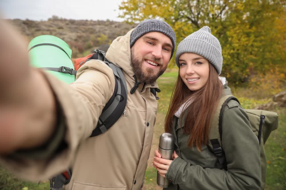 Smiling walkers with backpacks taking a selfie on a fall walk
